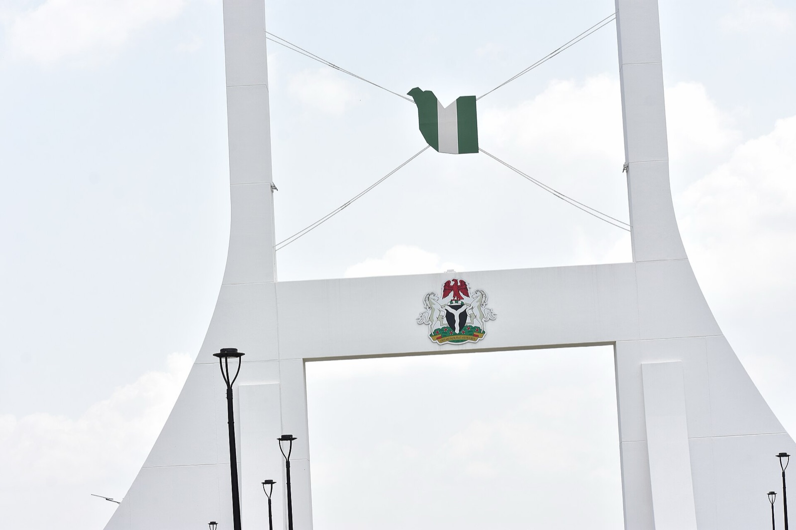 The Nigerian flag flying from the white arch of the Abuja City Gate