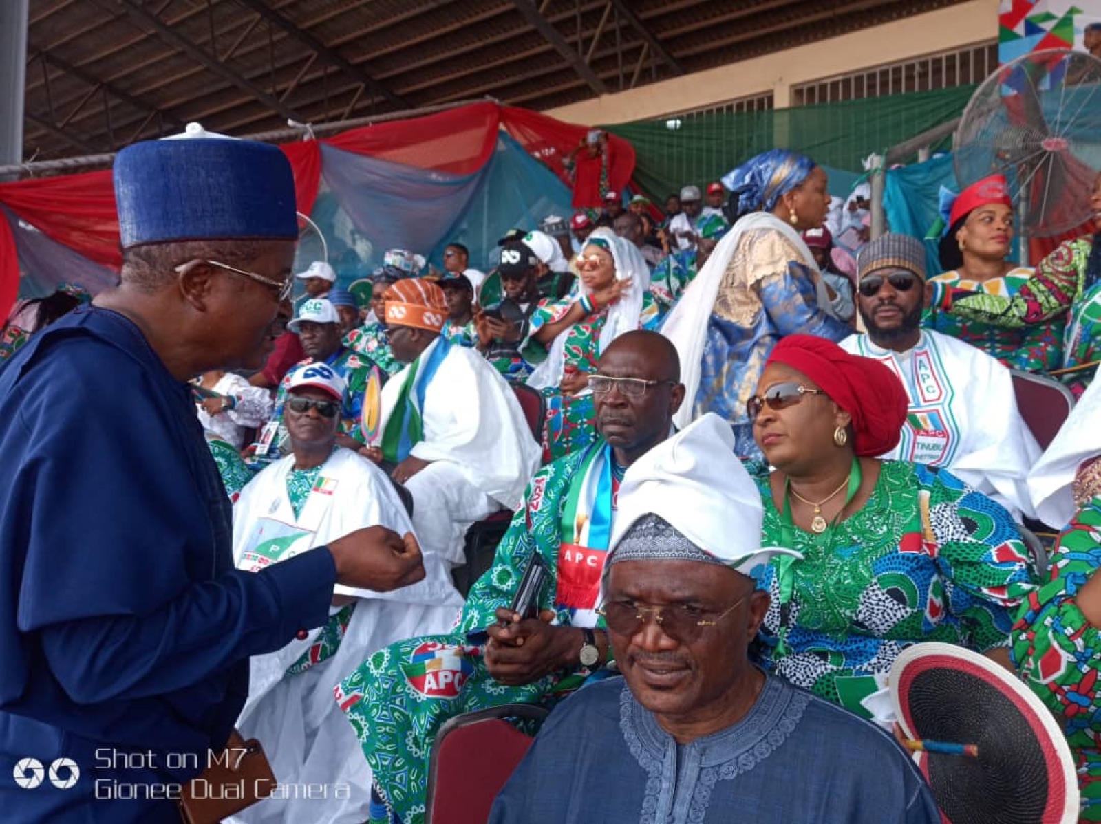 APC supporters in party colours seated in a stand at a campaign rally