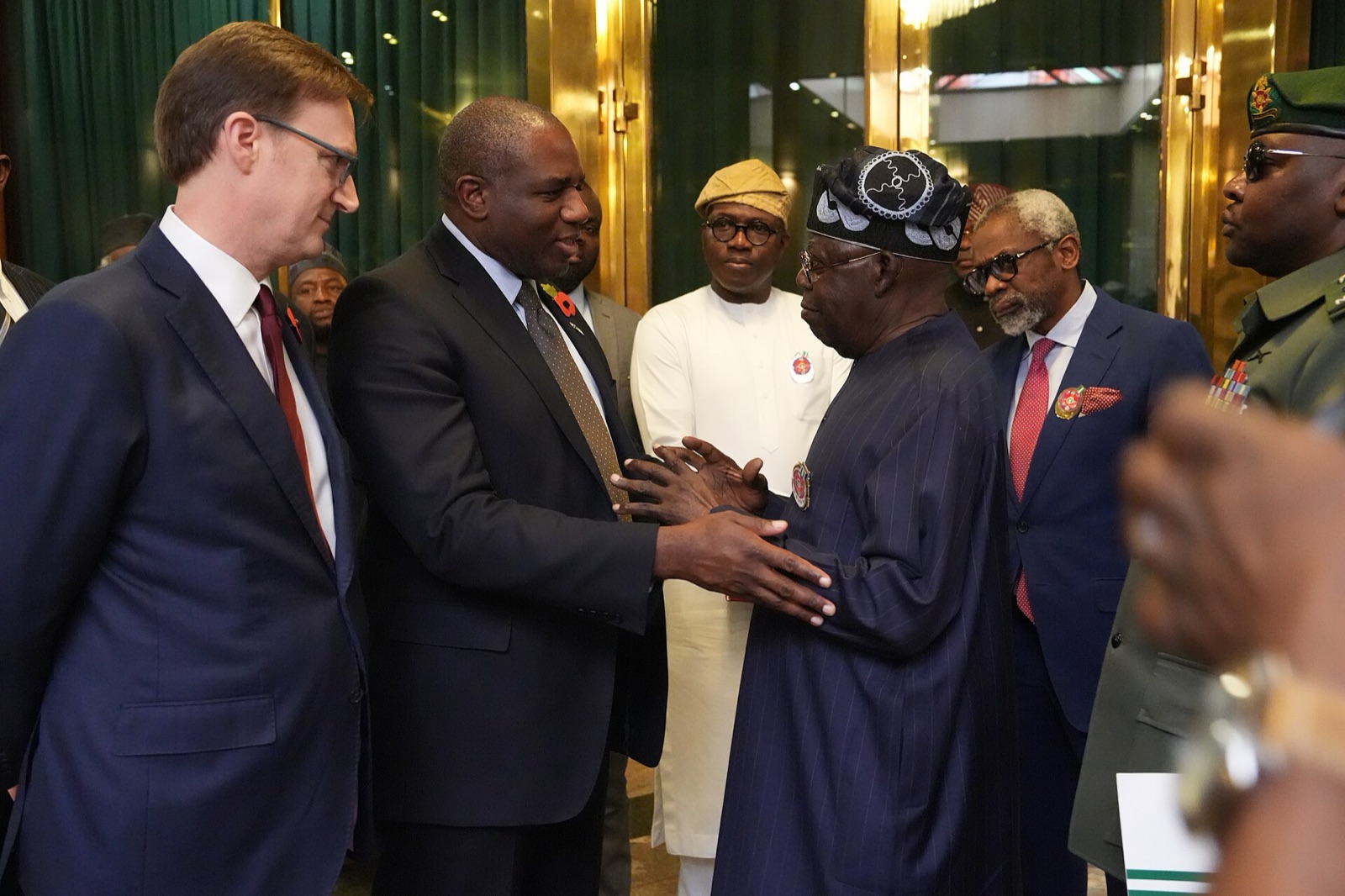 President Bola Ahmed Tinubu, in a dark agbada and cap, greets officials during a meeting in Abuja